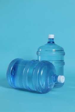 Açık mavi zemin üzerinde su olan soğutucu şişeler.