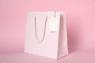Pembe arka planda boş etiketli alışveriş çantası.