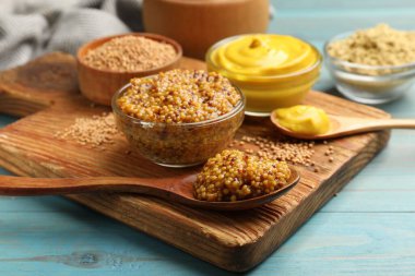 Açık mavi ahşap masada farklı hardal türleri, yakın plan.