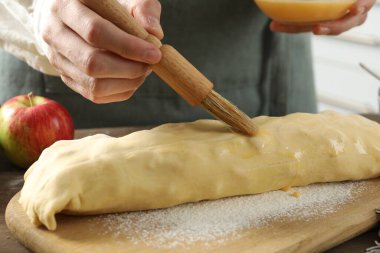 Mutfaktaki çiğ elmalı turtaya yumurta sarısı döken kadın, yakın plan.