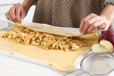 Mutfaktaki beyaz ahşap masada nefis elmalı turta yapan kadın.