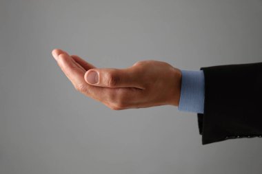 Gri arkaplanda bir şey tutan adam, yakın plan.