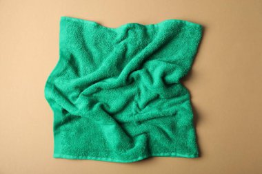 Bej arkaplanda yeşil havlu, üst görünümde.