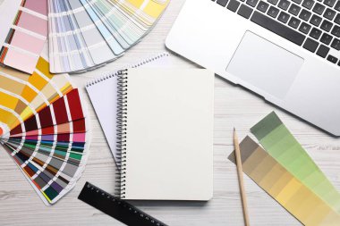 Boş eskiz defteri, dizüstü bilgisayar ve kırtasiye malzemesi beyaz ahşap masa, düz yatıyordu.