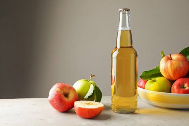 Cam şişede nefis elma şarabı ve arka planda gri masada elmalar. Metin için boşluk