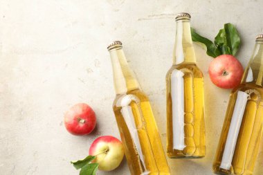 Cam şişelerde nefis elma şarabı ve gri desenli masada elmalar, düz yatak. Metin için boşluk