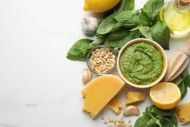 Taze pesto sosu kasede, malzemeler beyaz mermer masada, düz yerde. Metin için boşluk