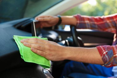 Salondaki yeşil mikrofiber bezle araba panelini silen adam, yakın plan.