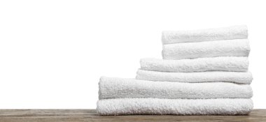 Ahşap masanın üzerinde beyaz arka plana karşı katlanmış havlu yığını, yakın plan. Metin için boşluk