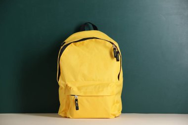 Tahtanın yanındaki masada sarı sırt çantası. Okula geri dön.