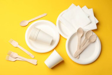 Sarı arkaplanda tek kullanımlık sofra takımı, düz konum