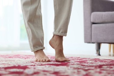 Kırmızı halıda çıplak ayakla yürüyen bir kadın.