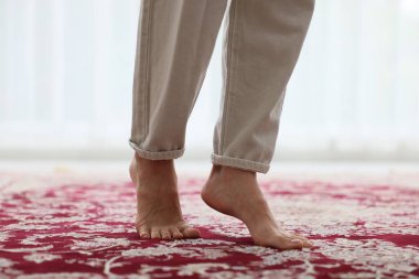 Kırmızı halıda çıplak ayakla yürüyen bir kadın.