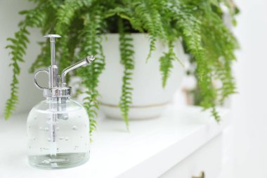 Sprey şişesi ve çiçekleri beyaz masaya koyun, yakın plan. Metin için boşluk