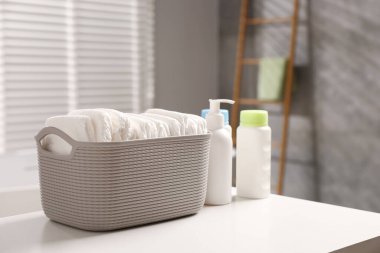 Bebek yıkama ürünleri ve bebek bezleri banyodaki beyaz masada.