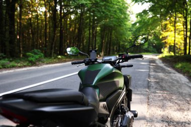 Modern siyah motosiklet açık yolda park edilmiş.