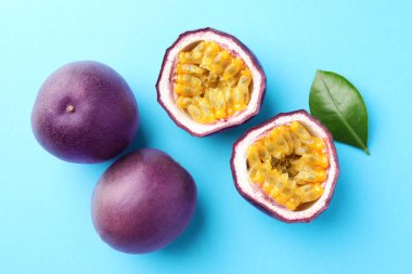 Açık mavi arka planda yeşil yapraklı taze tutku meyveleri, düz yatıyordu.