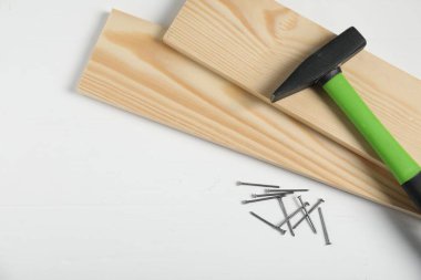 Çekiç, metal çiviler ve tahta tahtalar beyaz masada, düz yerde. Metin için boşluk