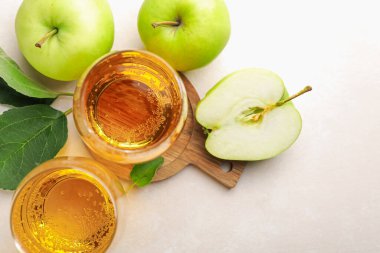 Taze elma şarabı cam ve elmalar bej masada, düz yerde.