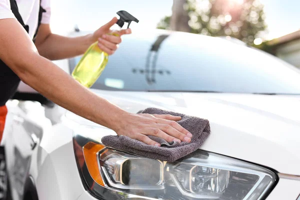 Dışarıdaki gri mikrofiber paçavralarla araba farlarını silen adam, yakın plan.