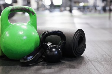 Spor salonunun zemininde kettlebell ve diğer spor aletleri var.