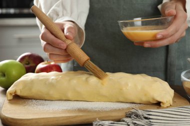 Mutfaktaki çiğ elmalı turtaya yumurta sarısı döken kadın, yakın plan.