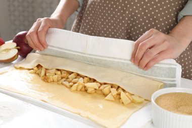 Mutfaktaki beyaz masada lezzetli elmalı turta yapan kadın, yakın plan.