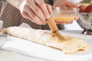 Mutfaktaki çiğ elmalı turtaya yumurta sarısı döken kadın, yakın plan.