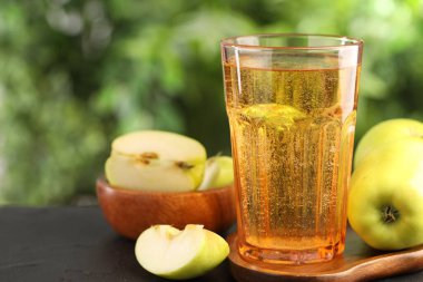 Lezzetli elma şarabı ve elmalar dışarıda, siyah masada, yakın plan.