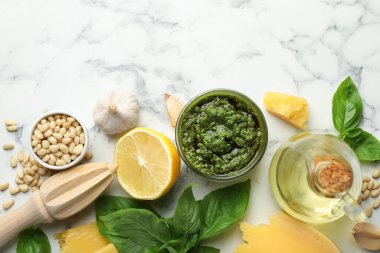 Taze pesto sosu kasede, malzemeler beyaz mermer masada, düz yerde. Metin için boşluk