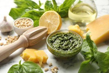 Taze pesto sosu kasede, malzemeler beyaz mermer masada, yakın plan.