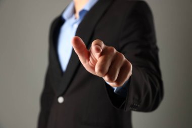 Adam gri arkaplanda bir şeye dokunuyor, yakın plan.