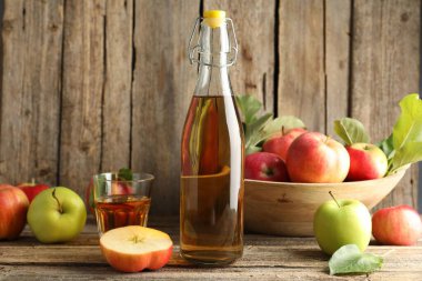 Şişe içinde nefis elma şarabı, ahşap masada cam ve elma.