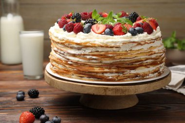 Delicious crepe cake with fresh berries on wooden table, closeup