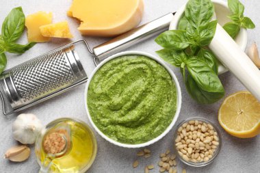 Taze pesto sosu kasede ve malzemeler açık gri masada, düz yerde.