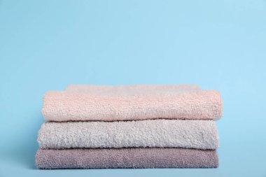 Açık mavi arka planda renkli havlular yığını, yakın plan. Metin için boşluk