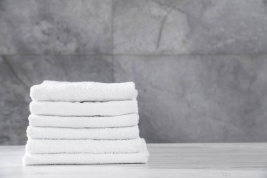 Gri duvara karşı açık ahşap masada katlanmış havlular, yakın plan. Metin için boşluk