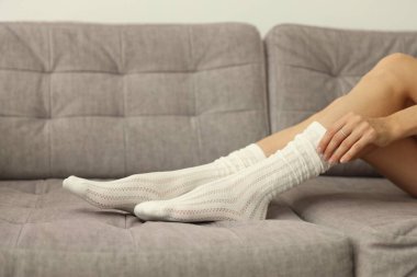 Çoraplı kadın, evdeki gri koltukta, yakın plan.