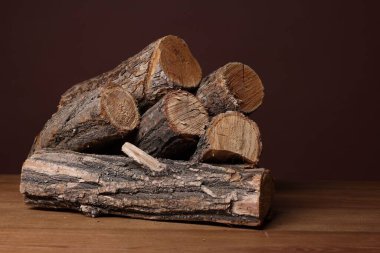 Ahşap masa üzerine kesilmiş odun yığını kahverengi arka plana karşı, yakın plan
