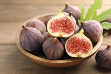 Taze incir ve yeşil yaprak ahşap masada, yakın plan.