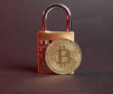 Gri arkaplanda kırmızı ışıkta Bitcoin ve asma kilit, yakın plan