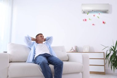 Klimalı kanepede rahat sıcaklığın tadını çıkaran bir adam.