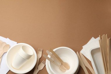 Kahverengi arka planda tek kullanımlık sofra takımı var. Metin için boşluk