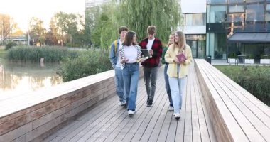 Bir grup genç açık havada göl kenarında yürüyor.