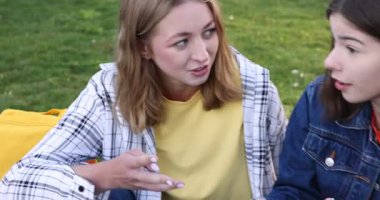 Bir grup genç parkta birlikte vakit geçiriyorlar, kameralar sağa kayıyor.