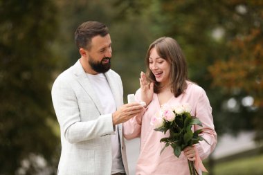 Nişan yüzüklü bir adam kız arkadaşına dışarıda evlenme teklif ediyor.