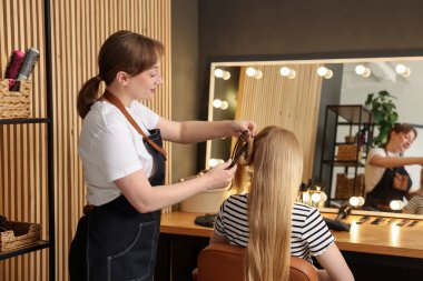 Profesyonel kuaför müşteriyle kuaförde çalışıyor.