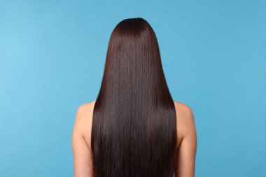 Açık mavi arkaplanda katman prosedüründen sonra güzel, pürüzsüz saçlı kadın.