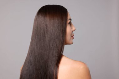 Açık gri arkaplandaki laminasyon prosedüründen sonra güzel pürüzsüz saçlı kadın