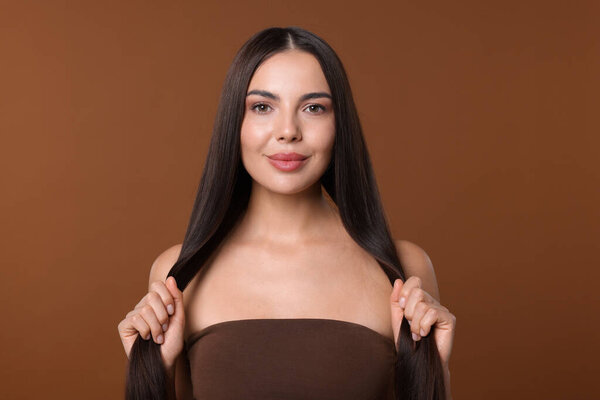 Woman with beautiful smooth hair after lamination procedure on brown background